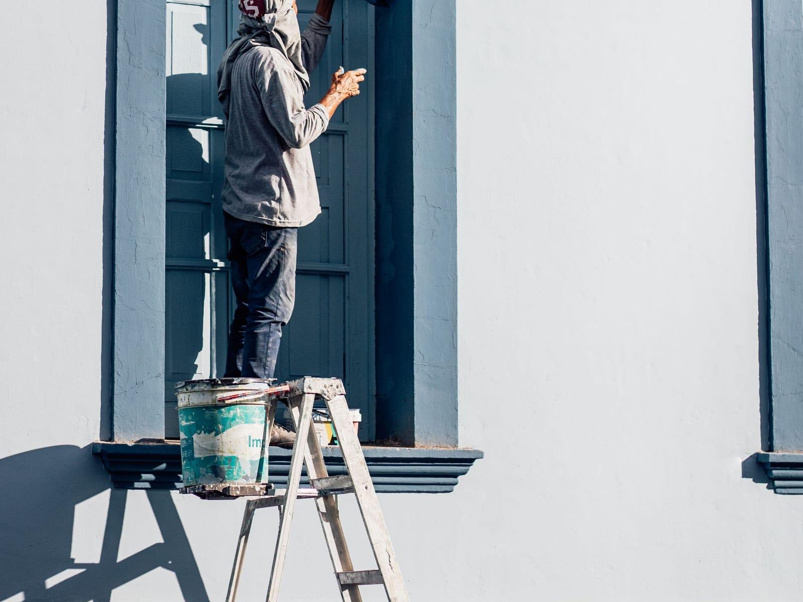 Pinsel lackiert die Kante eines Fensterrahmens aus Holz