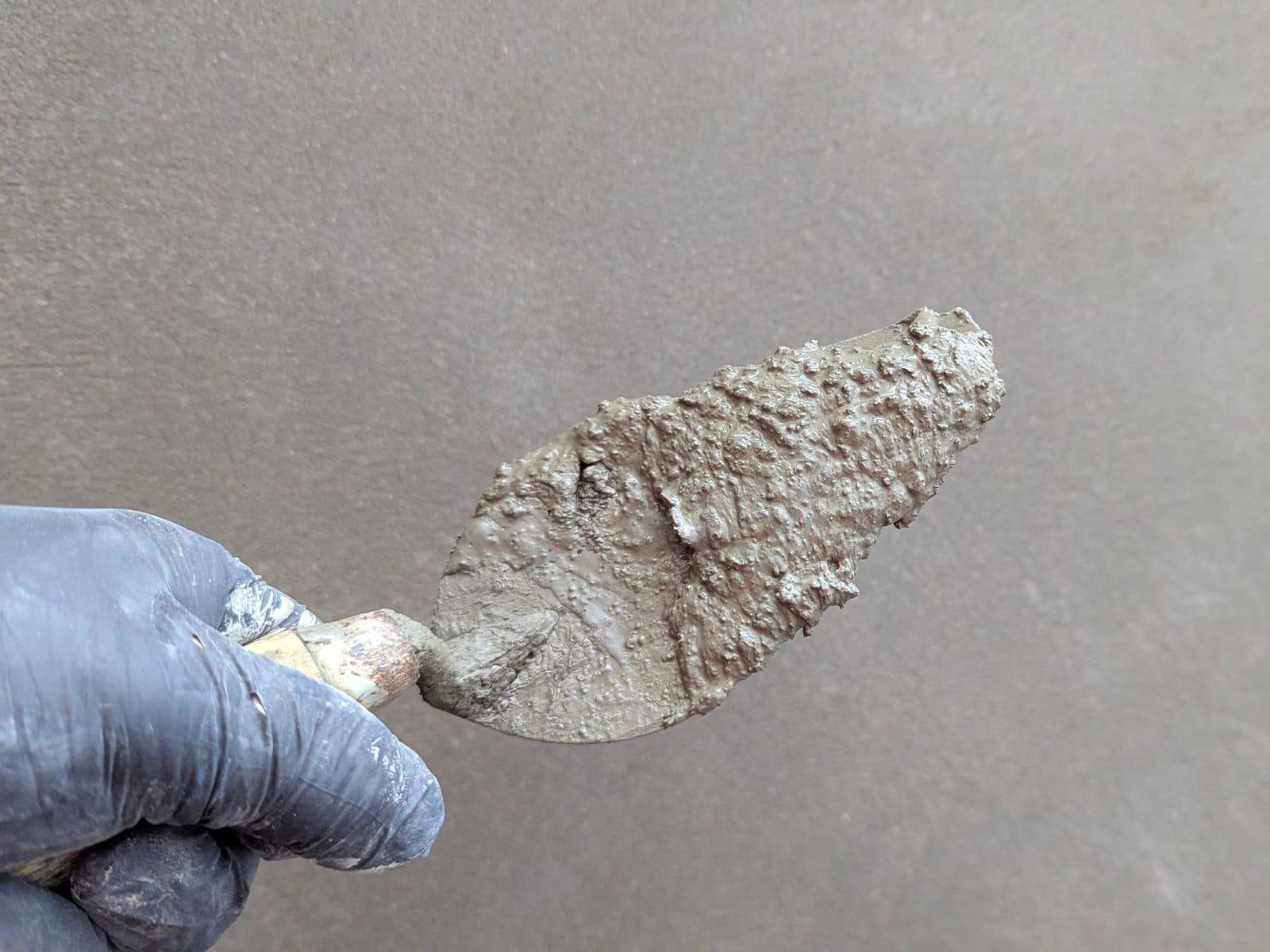 Glättkelle zieht Spachtelmasse über eine Wandfläche